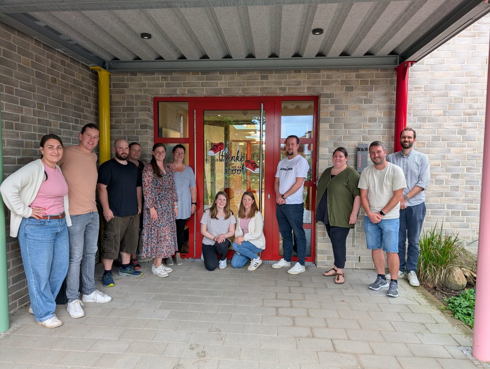 Gruppenfoto der Gründungsmitglieder vor dem roten Eingang der Kita Flinke Fööt